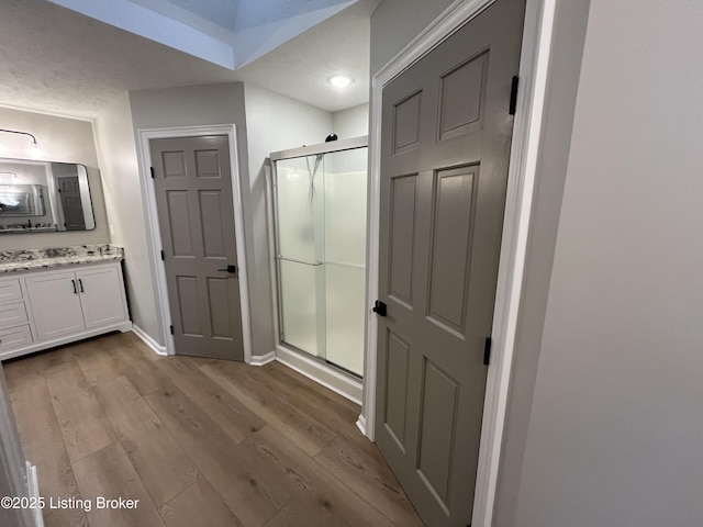 bathroom with a stall shower, baseboards, wood finished floors, and vanity