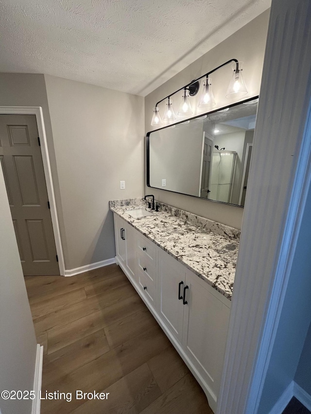 bathroom featuring a shower stall, vanity, a textured ceiling, and wood finished floors