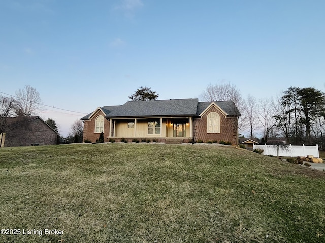 ranch-style house featuring brick siding, a front yard, and fence