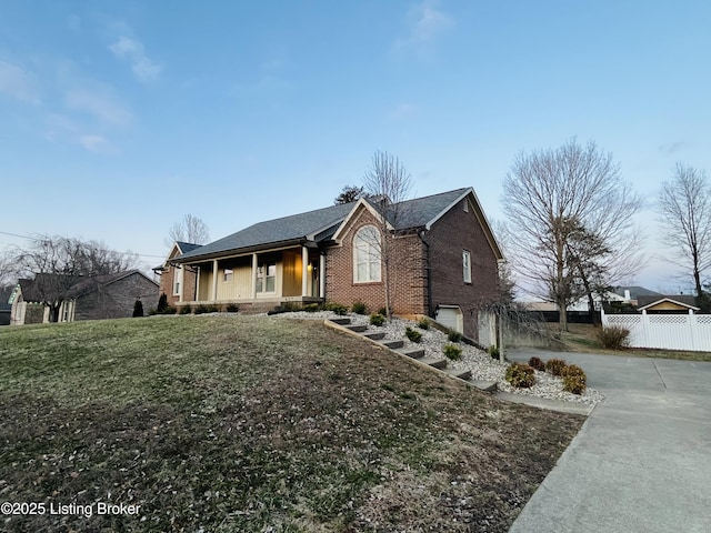 view of front facade with an attached garage, brick siding, fence, concrete driveway, and a front yard