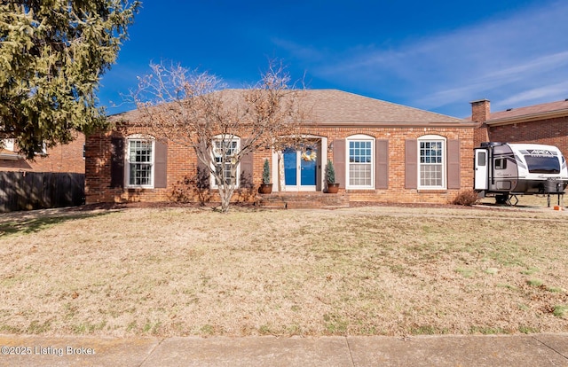 single story home featuring a shingled roof, a front lawn, and brick siding