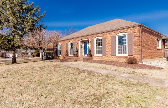 single story home with a front yard, brick siding, and roof with shingles