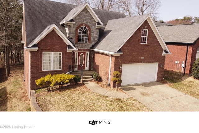 view of front of home with driveway, stone siding, roof with shingles, an attached garage, and brick siding