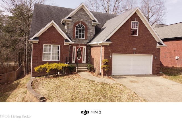 traditional home featuring concrete driveway, stone siding, roof with shingles, an attached garage, and brick siding