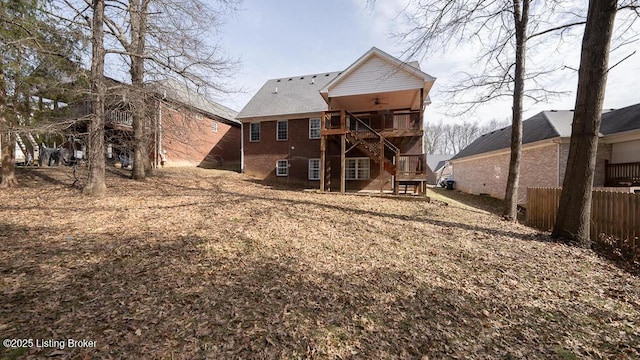 rear view of house featuring stairway, fence, and brick siding