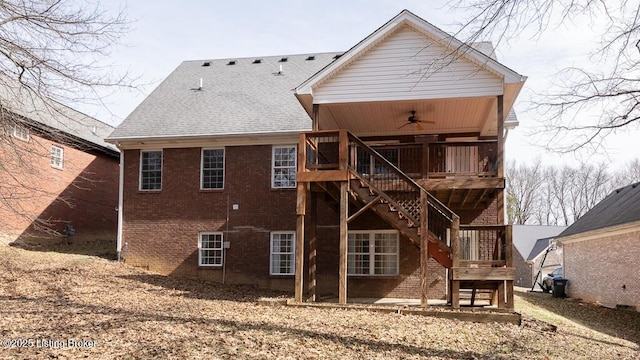 back of property with a ceiling fan, stairway, roof with shingles, a wooden deck, and brick siding