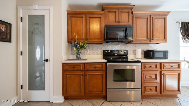 kitchen featuring black microwave, brown cabinets, and stainless steel range with electric cooktop