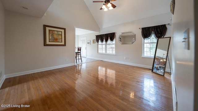 unfurnished living room with ceiling fan, high vaulted ceiling, hardwood / wood-style flooring, and baseboards