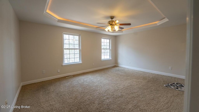 empty room featuring carpet, baseboards, and a raised ceiling