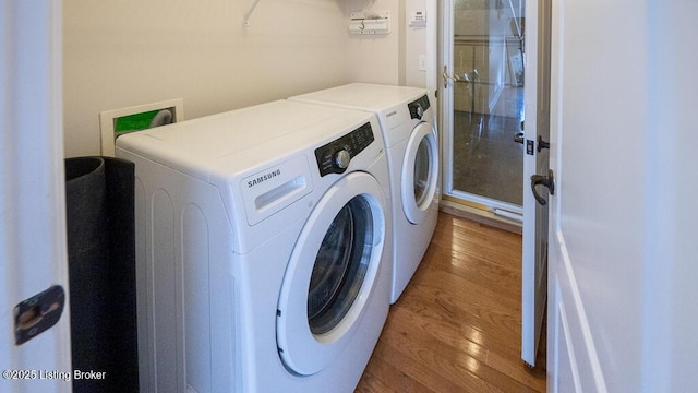 clothes washing area featuring laundry area, washer and clothes dryer, and wood finished floors