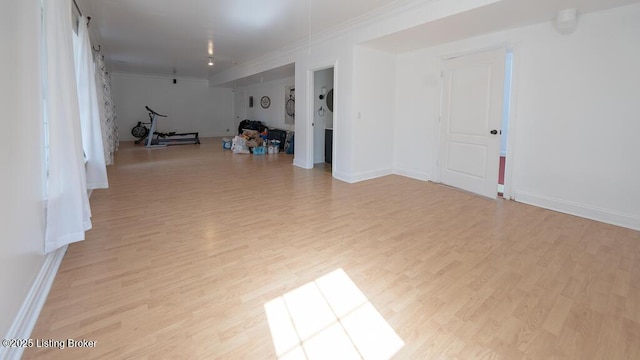 interior space featuring ornamental molding, light wood-type flooring, and baseboards