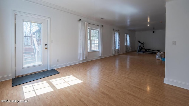 interior space featuring baseboards, wood finished floors, and crown molding