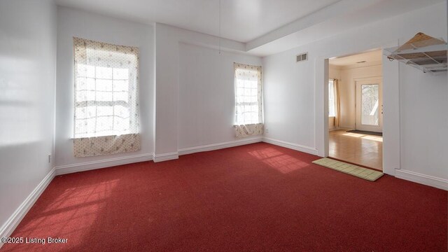 carpeted spare room featuring visible vents and baseboards