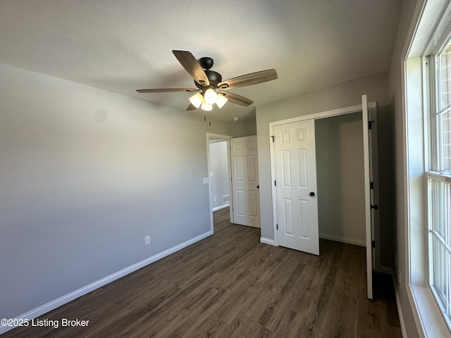 unfurnished bedroom featuring a ceiling fan, baseboards, dark wood-style flooring, a closet, and a textured ceiling