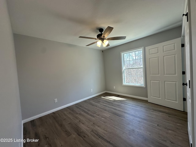 unfurnished bedroom with dark wood-style floors, a ceiling fan, and baseboards