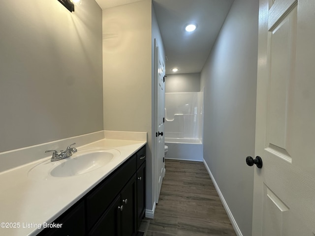 full bath with vanity, wood finished floors, baseboards, bathtub / shower combination, and toilet