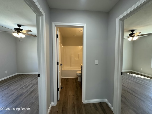 corridor with baseboards and dark wood-style flooring