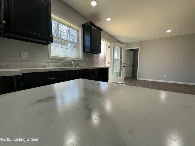 kitchen with wood finished floors, recessed lighting, dark cabinets, and baseboards