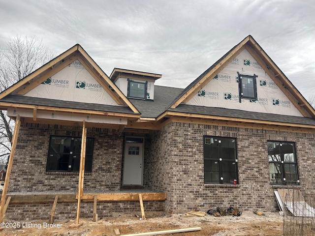 property in mid-construction with brick siding, covered porch, and a shingled roof