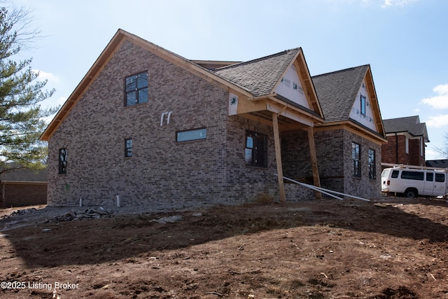 view of home's exterior with brick siding and roof with shingles