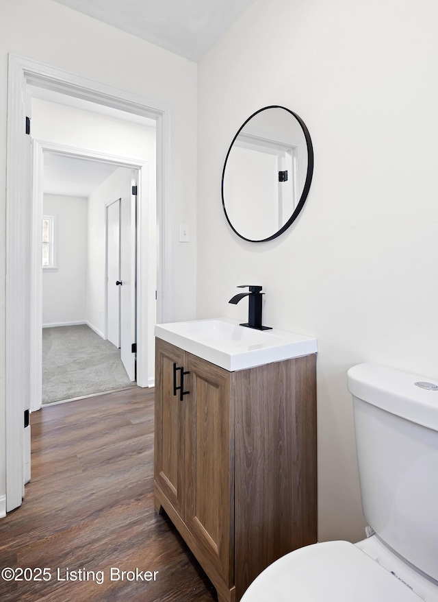 bathroom with toilet, wood finished floors, and vanity