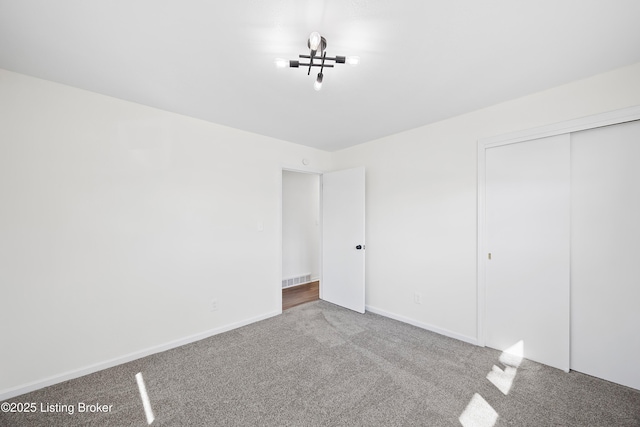 unfurnished bedroom featuring a closet, carpet flooring, visible vents, and baseboards