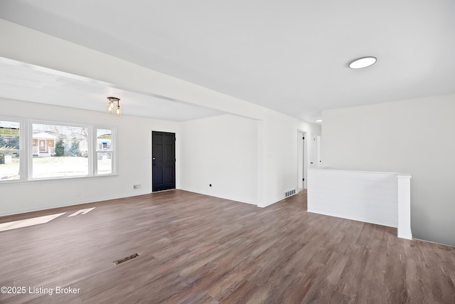 empty room with baseboards, visible vents, and wood finished floors