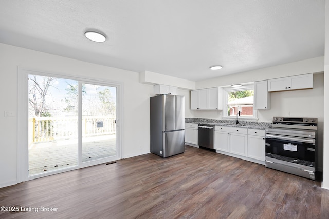 kitchen featuring dark wood-style floors, visible vents, appliances with stainless steel finishes, white cabinetry, and a sink