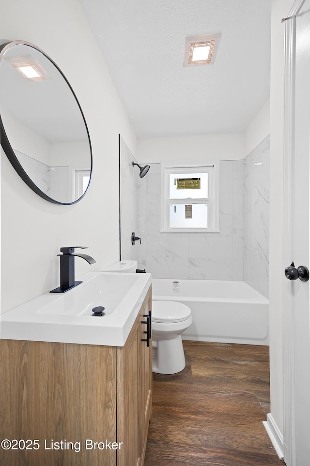 bathroom with visible vents, toilet, wood finished floors,  shower combination, and vanity