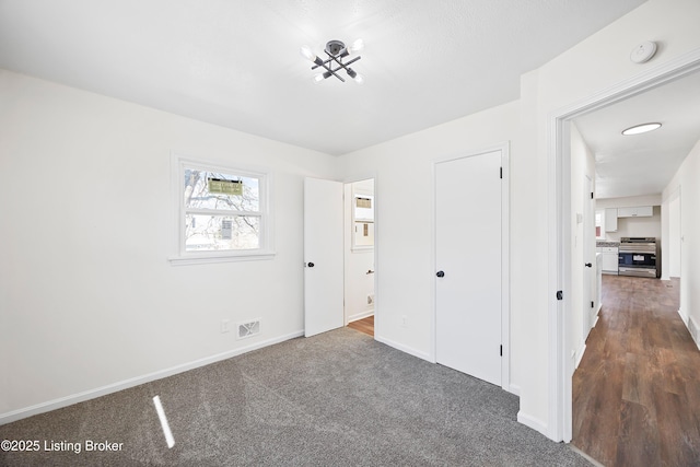 unfurnished bedroom with baseboards, visible vents, and dark colored carpet