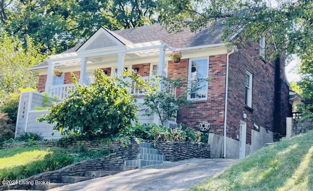 view of front facade featuring brick siding and a porch