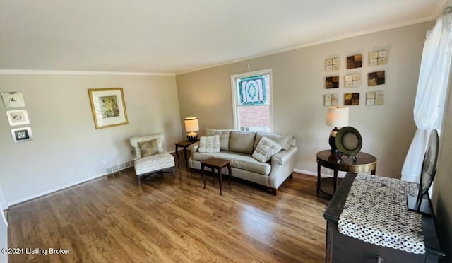 living area with ornamental molding, wood finished floors, and baseboards