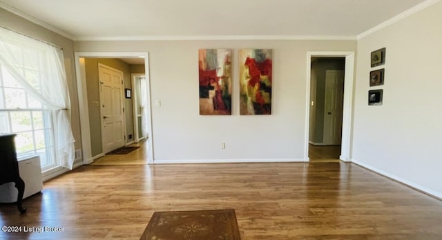 interior space with crown molding, baseboards, and wood finished floors