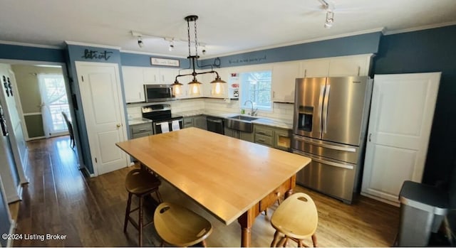 kitchen with appliances with stainless steel finishes, white cabinets, dark wood finished floors, and ornamental molding