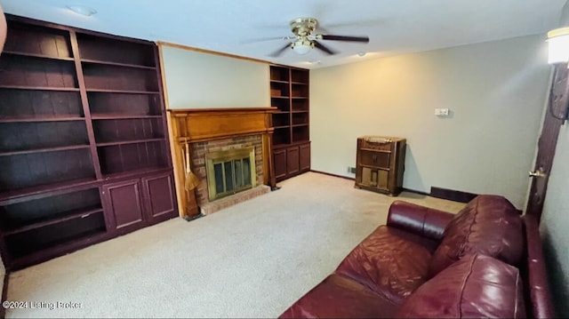 living area featuring built in features, baseboards, a glass covered fireplace, ceiling fan, and carpet flooring