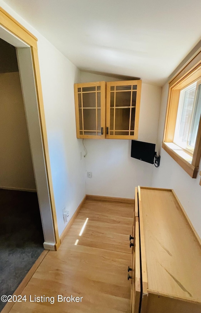 kitchen featuring glass insert cabinets, lofted ceiling, baseboards, and wood finished floors