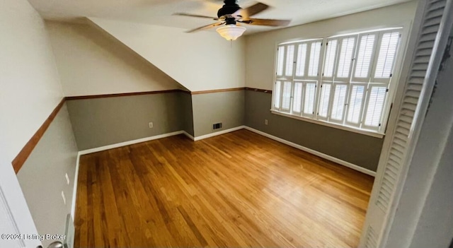 additional living space with a ceiling fan, wood finished floors, visible vents, and baseboards