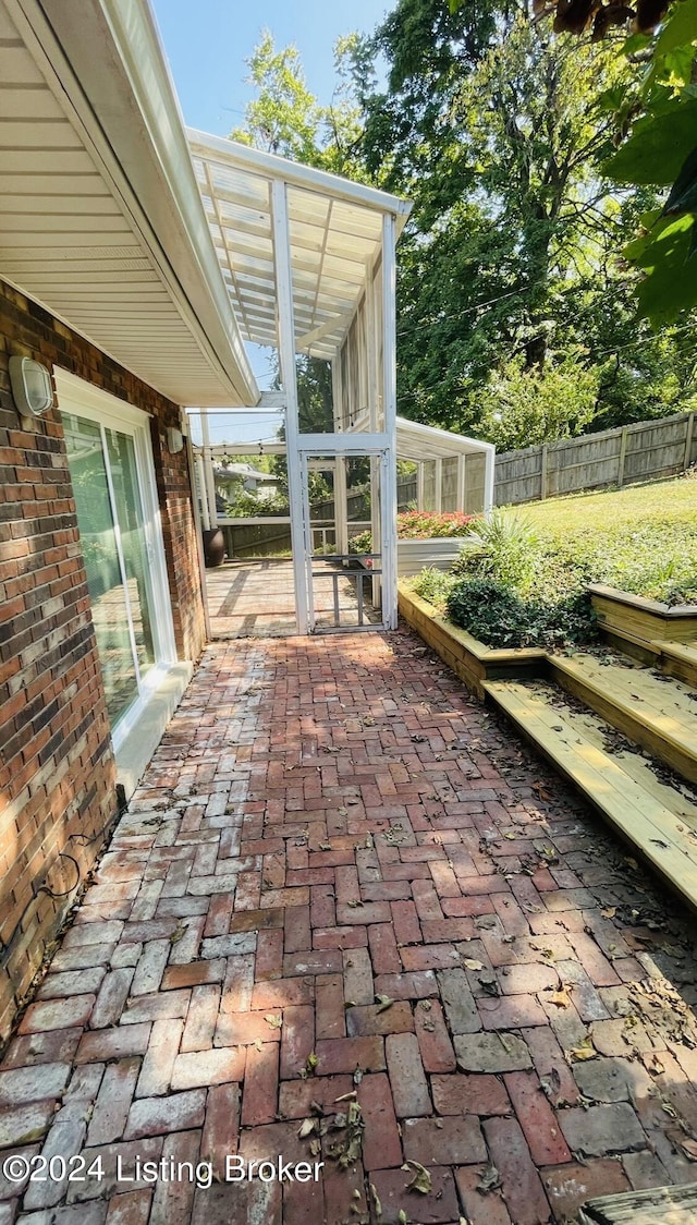 view of patio featuring fence and a sunroom