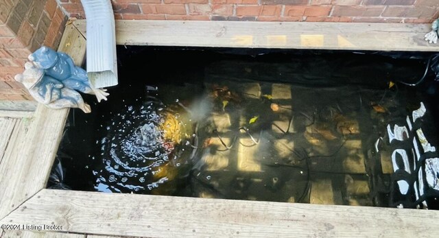 exterior details with brick siding, crawl space, and a small pond