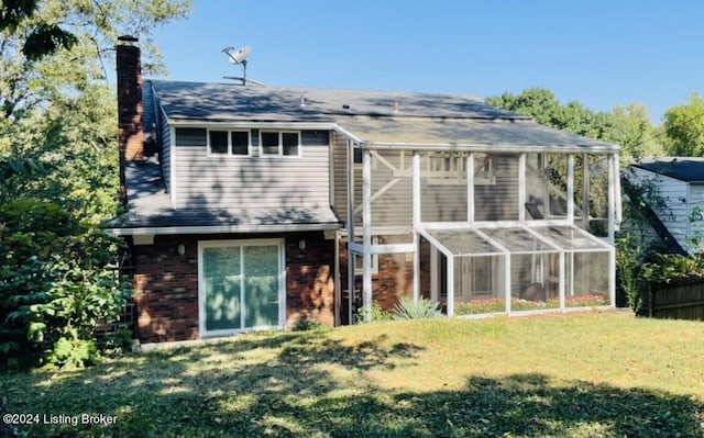 back of property with brick siding, a yard, a chimney, and fence