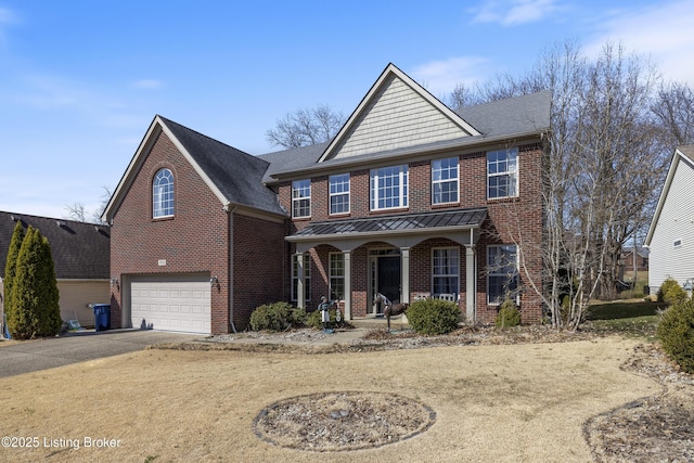 view of front of home with driveway, a standing seam roof, covered porch, an attached garage, and brick siding