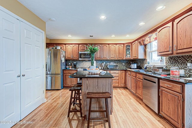kitchen featuring appliances with stainless steel finishes, a breakfast bar area, light wood-type flooring, and brown cabinets