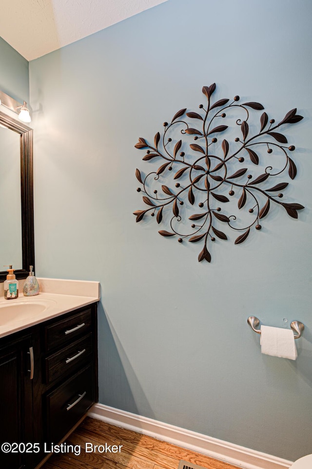 bathroom with baseboards, wood finished floors, and vanity