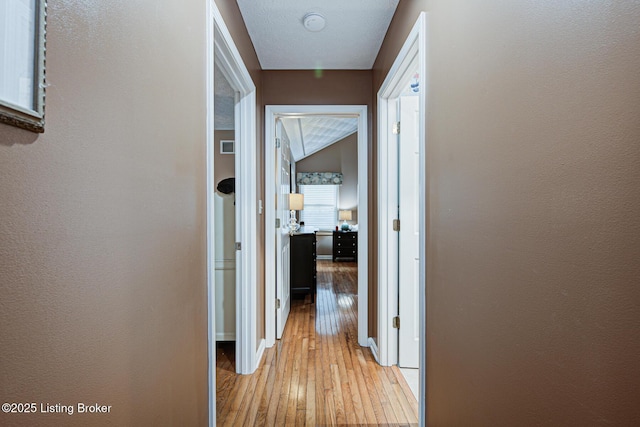 hallway with light wood finished floors and baseboards