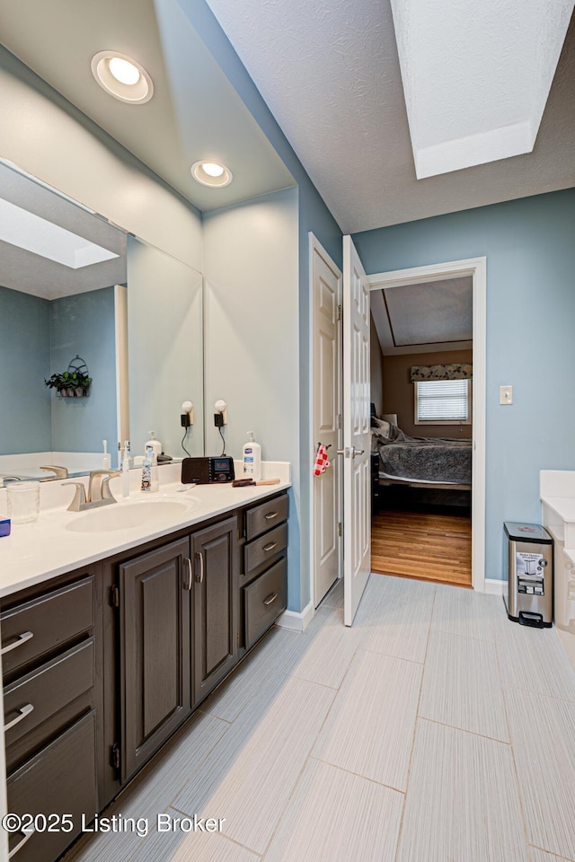 ensuite bathroom featuring recessed lighting, ensuite bath, baseboards, and vanity