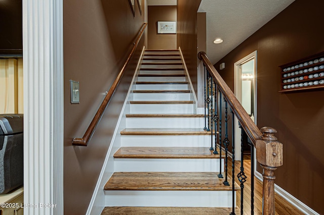 stairway with a textured ceiling and recessed lighting