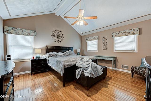 bedroom featuring vaulted ceiling with beams, light wood finished floors, visible vents, a ceiling fan, and baseboards