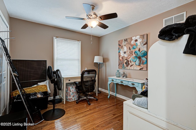 office featuring arched walkways, visible vents, a ceiling fan, a textured ceiling, and hardwood / wood-style flooring