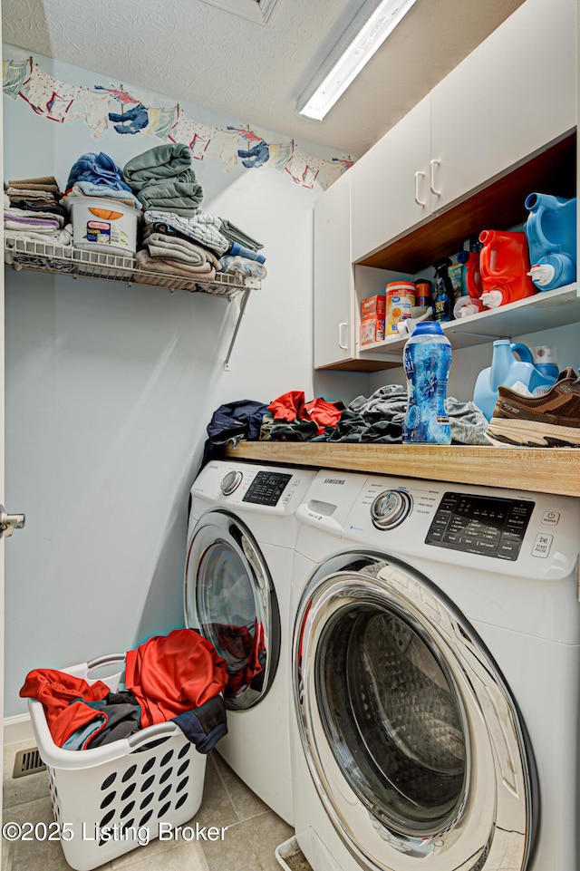 clothes washing area featuring cabinet space, washer and clothes dryer, a textured ceiling, and light tile patterned flooring