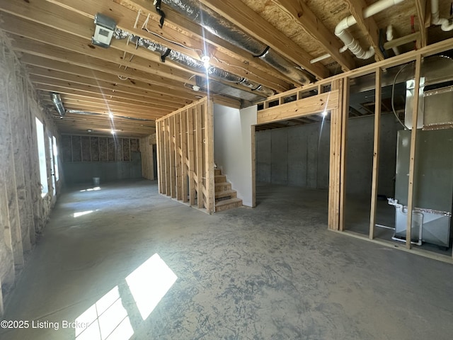 unfinished basement featuring heating unit and stairs